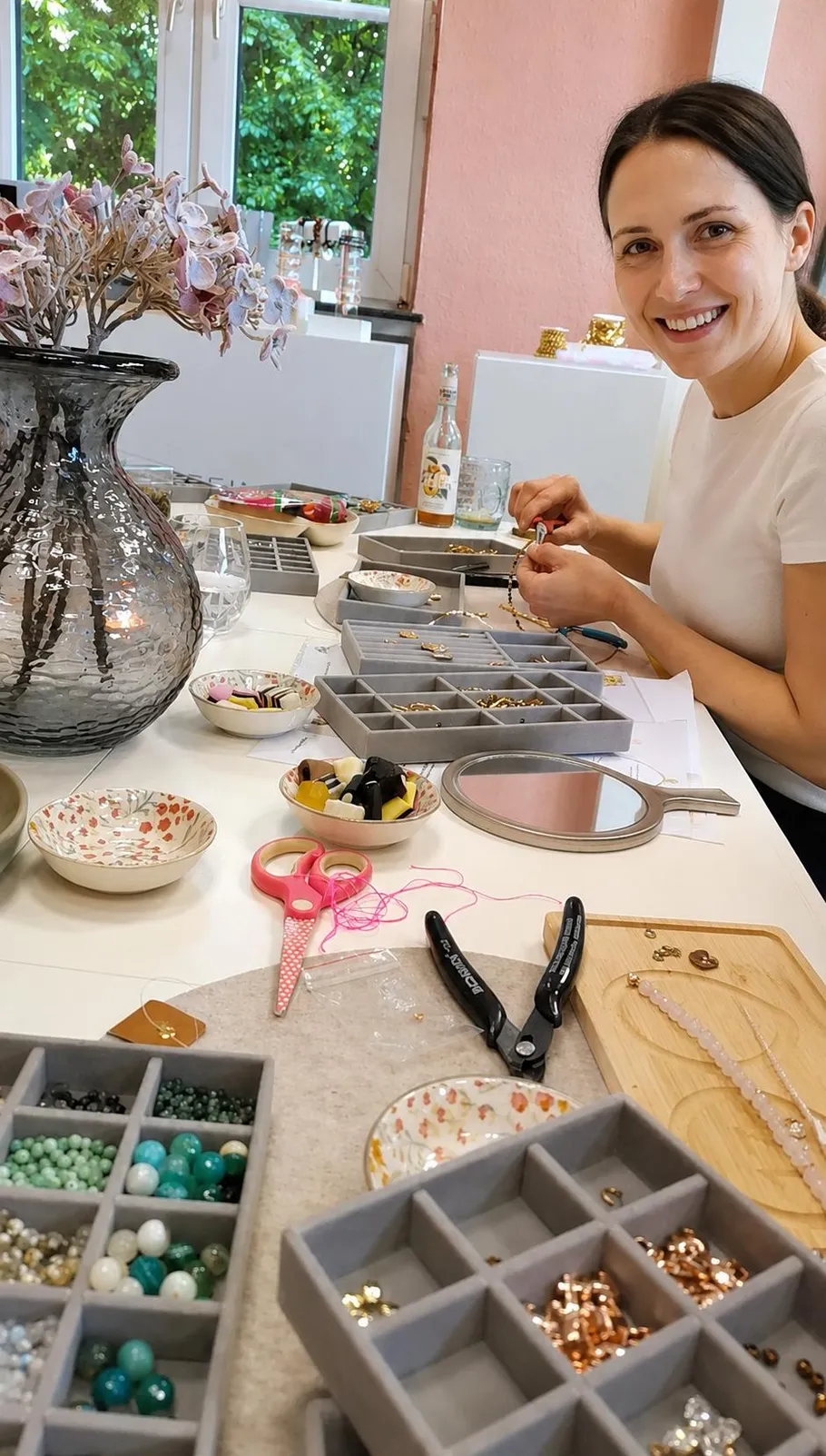 Woman crafting jewelry at a table with tools.