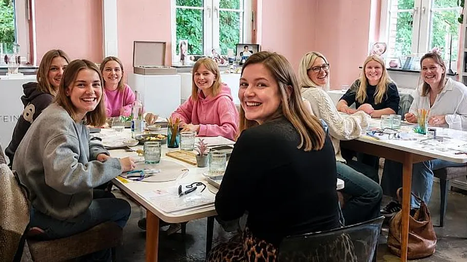 Gruppe Frauen lächeln um Tisch drinnen.