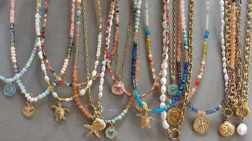 Bunte Perlenketten mit goldenen Anhängern ausgestellt.
