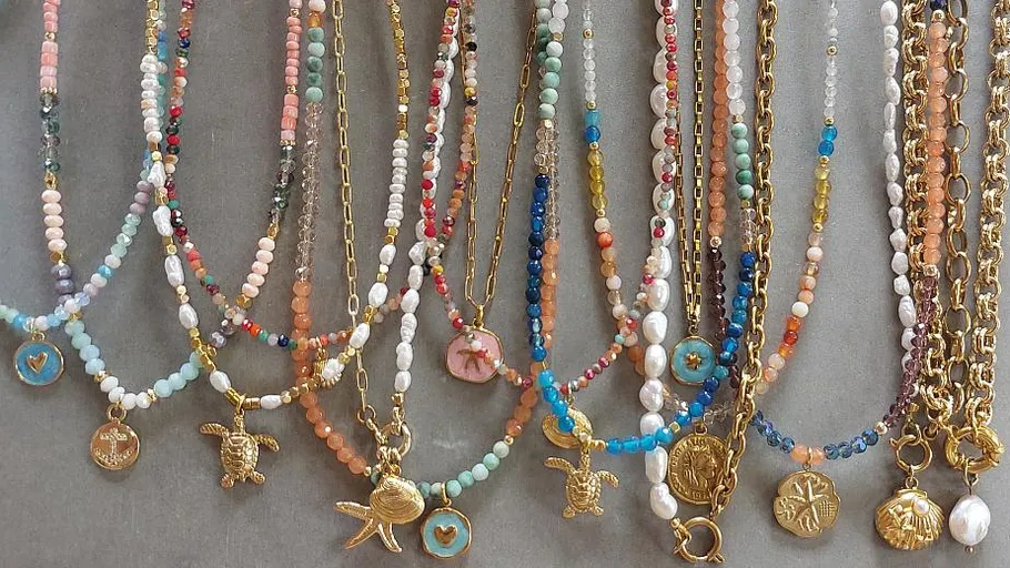 Colorful beaded necklaces with gold charms displayed.