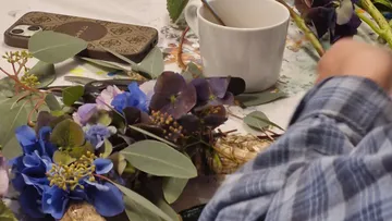 Person arrangiert Blumen auf einem Tisch.