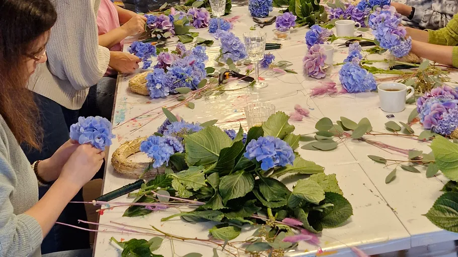 Personen basteln Blumenarrangements an einem Tisch.