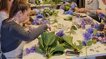 People arranging flowers at a table workshop.