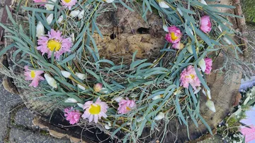 Blumenkranz auf Baumstumpf im Freien.