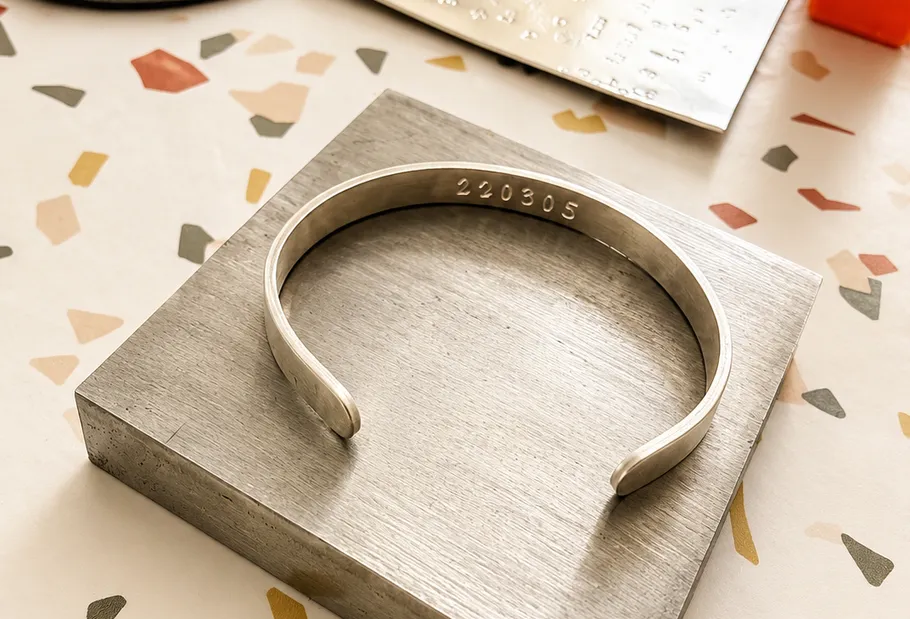 Silver bracelet with '220305' on metal block.