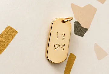 Gold pendant engraved with numbers on paper.