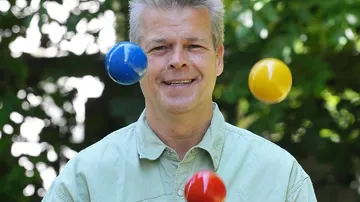 Mann jongliert mit bunten Bällen im Freien.