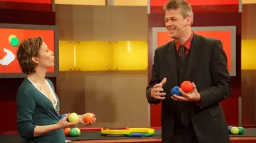 Zwei Personen jonglieren Bälle im Fernsehstudio.