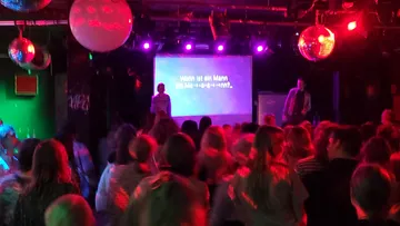 Publikum schaut Karaoke-Performance in buntem Club.