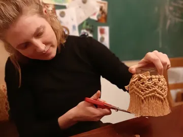 Woman cuts fringed fabric on a glass. Backgrounds show notes.