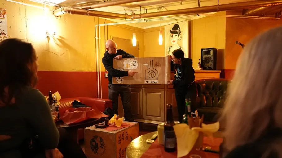 Two people presenting poster in cozy bar.