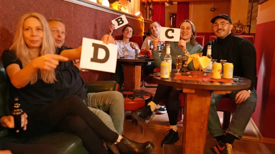 Group of people holding letter cards in a bar.