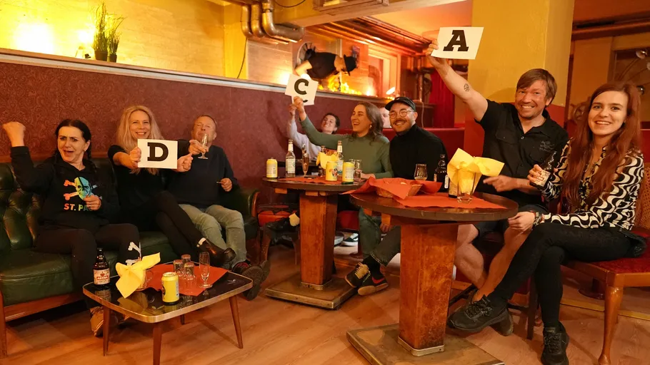 People in a bar holding letter cards.