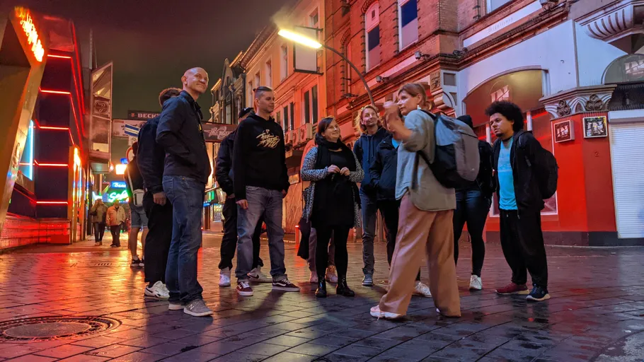 Group of people standing on city street at night.