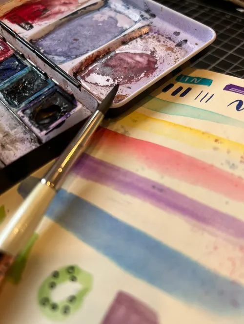 Aquarellpalette, Pinsel und gemalte Streifen.