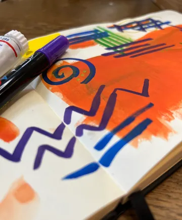 Bunte Kritzeleien im Notizbuch mit Stiften.