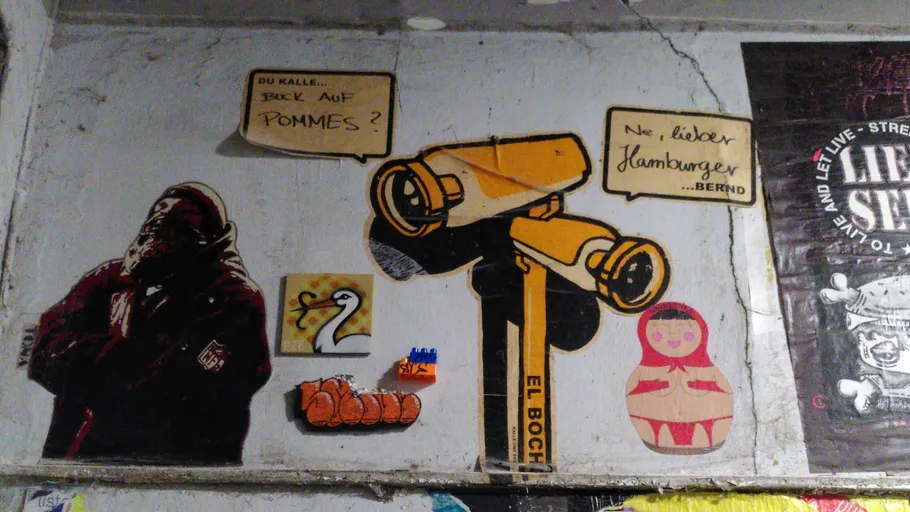 Graffiti on wall with various colorful stickers.