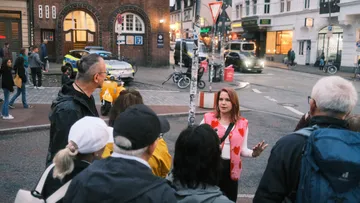 Frau spricht zu Gruppe auf Stadtstraße.