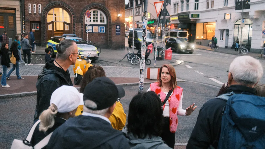 Woman speaking to group on city street.