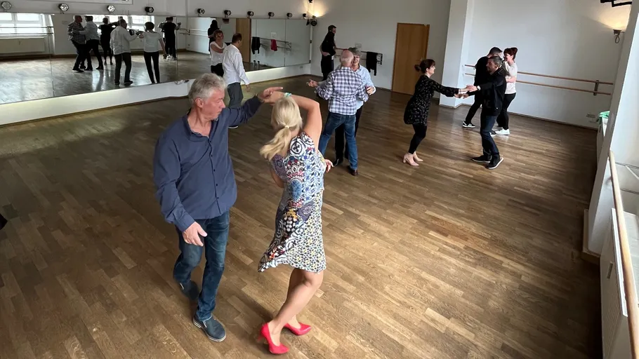 Couples dancing in a studio with mirrors.
