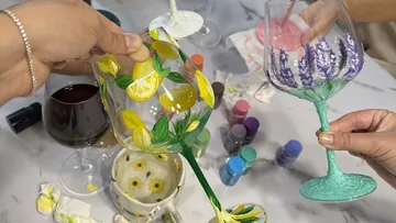 Decorated wine glasses being painted with floral designs.