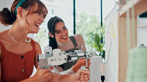 Zwei Frauen gestalten Kunst mit Tufting-Werkzeug drinnen.
