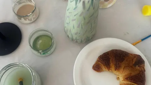 Croissant auf Teller mit Kerzen und Vase.