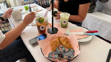 Menschen bemalen Keramik an einem Tisch mit Getränken.