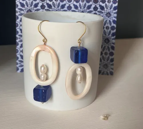 Elegant earrings hanging on white cup.
