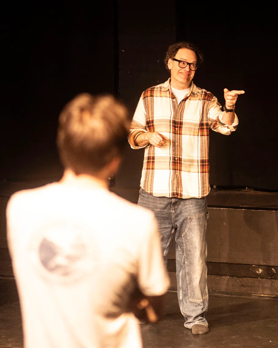 Man pointing during theater rehearsal on stage.