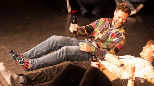 People laughing and lying on stage with drinks.
