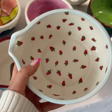 Hand hält Schüssel mit Erdbeermuster.