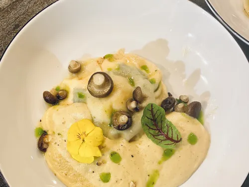 A plate of filled dumplings decorated with mushrooms.