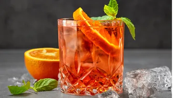 Orange cocktail with mint on grey background.