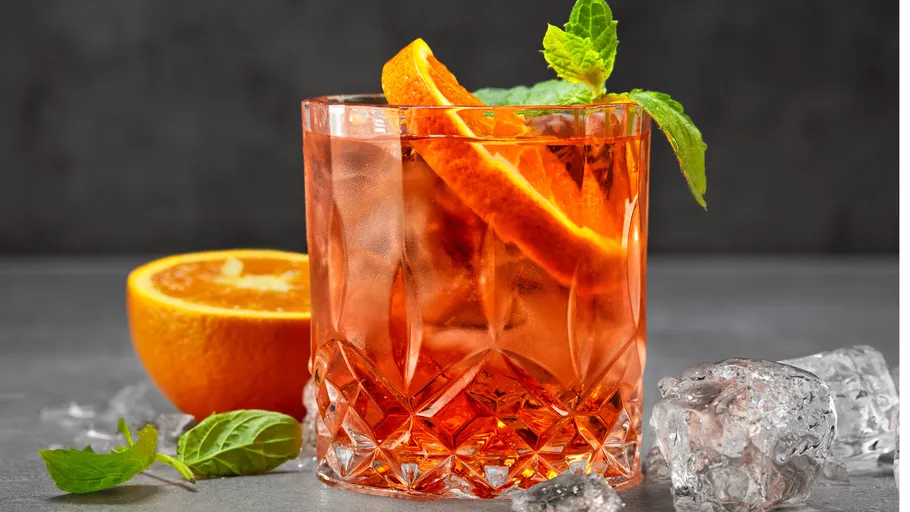 Orangencocktail mit Minze auf grauem Hintergrund.