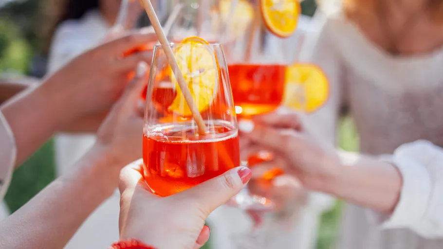 Hands toasting with glasses of orange drinks.