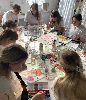 Gruppe malt mit Aquarellen am Tisch.
