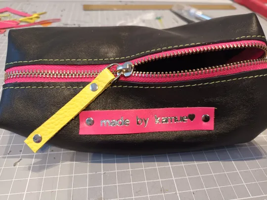 Handgemachte schwarze Tasche mit pinkem Reißverschluss.