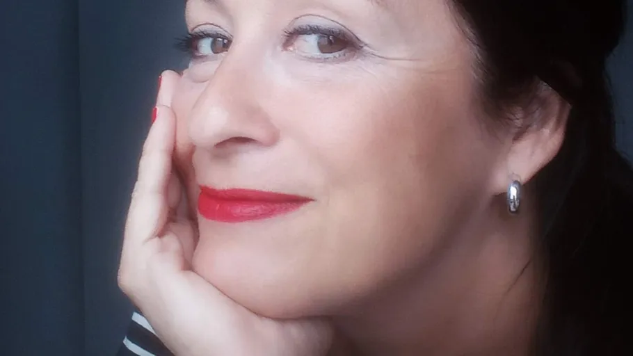 Woman smiling, hand on cheek, indoors.