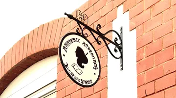 Round sign with butterfly and text on wall.