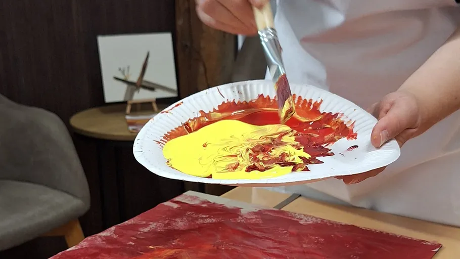 Person mixes paint on a paper plate.
