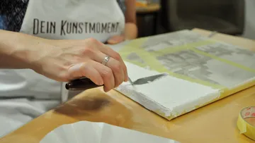 Person malt auf Leinwand mit einem Malmesser.