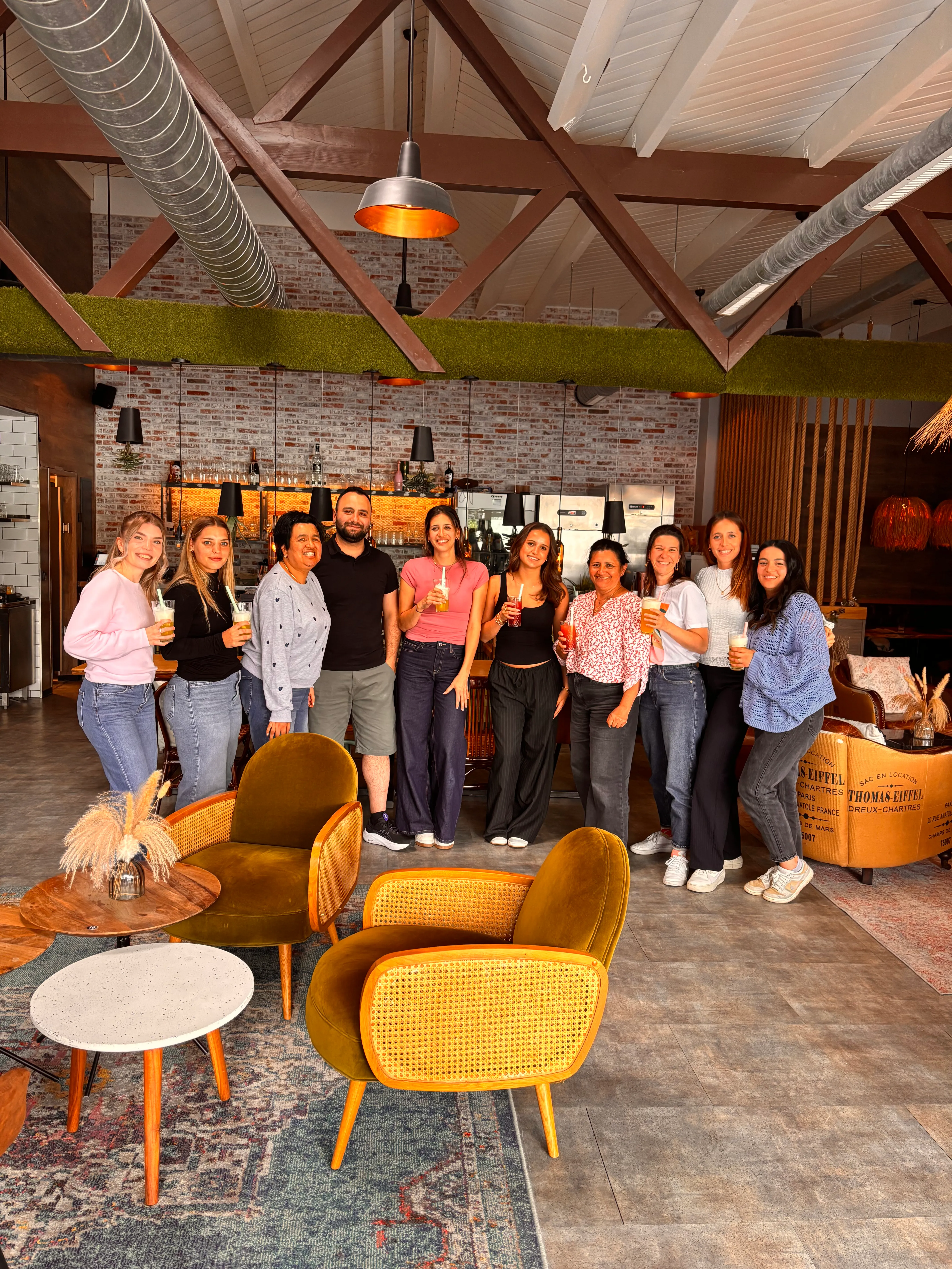 Gruppe steht drinnen mit Getränken, gemütliches Café-Ambiente.