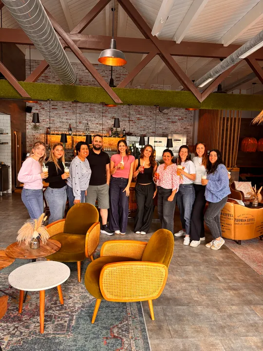 Gruppe steht drinnen mit Getränken, gemütliches Café-Ambiente.