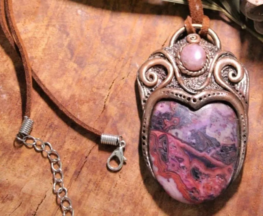 Heart-shaped pendant with intricate design on wood.