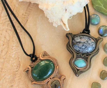 Two gemstone pendants on a wooden surface.