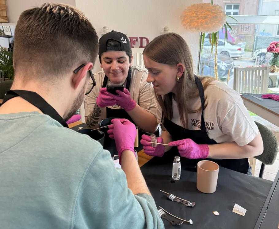 Three people crafting with tools and gloves indoors.