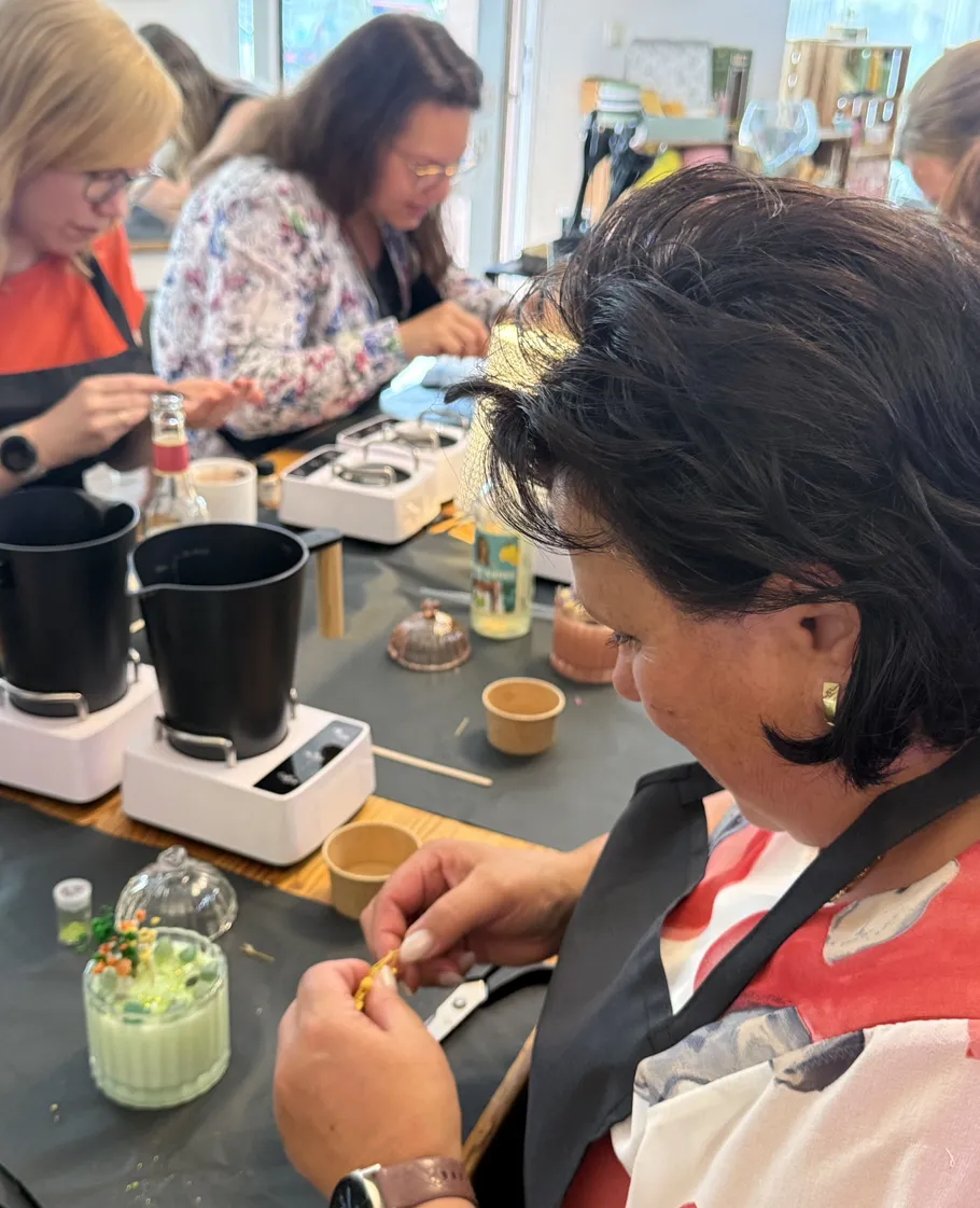 Frauen basteln Kerzen an einem Workshop-Tisch.