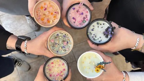 Hands holding decorated candles in group circle.
