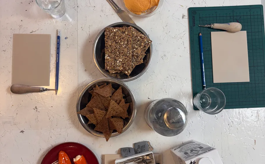 Kunstwerkzeuge und Snacks auf strukturierter weißer Tisch.